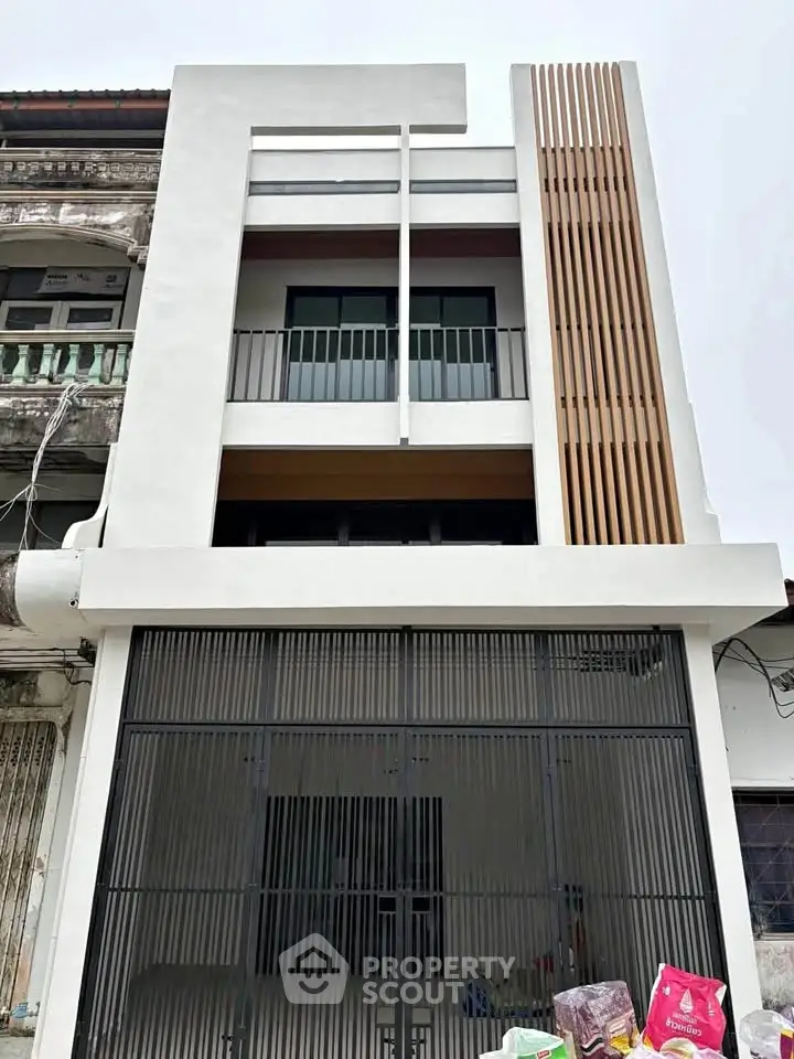 Modern three-story townhouse with sleek facade and balcony in urban setting.