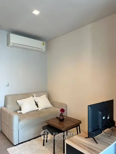 Cozy living room with modern sofa, air conditioning, and flat-screen TV, perfect for relaxation.