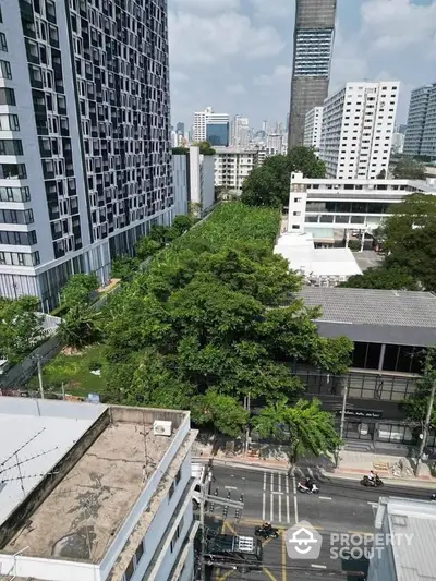 Stunning cityscape view from high-rise building with lush greenery and urban skyline.