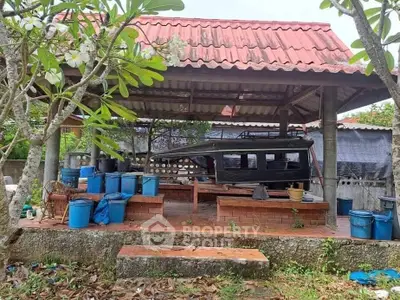 Outdoor covered area with tiled roof and various containers, ideal for storage or gardening.