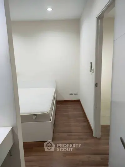 Cozy bedroom with wooden flooring and minimalist design, perfect for a serene living experience.