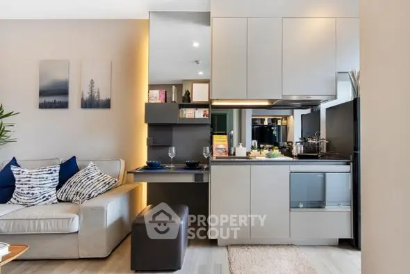 Modern living room with integrated kitchen, stylish decor, and cozy seating area.