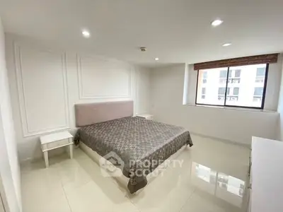 Spacious modern bedroom with large window and elegant decor in a high-rise apartment.