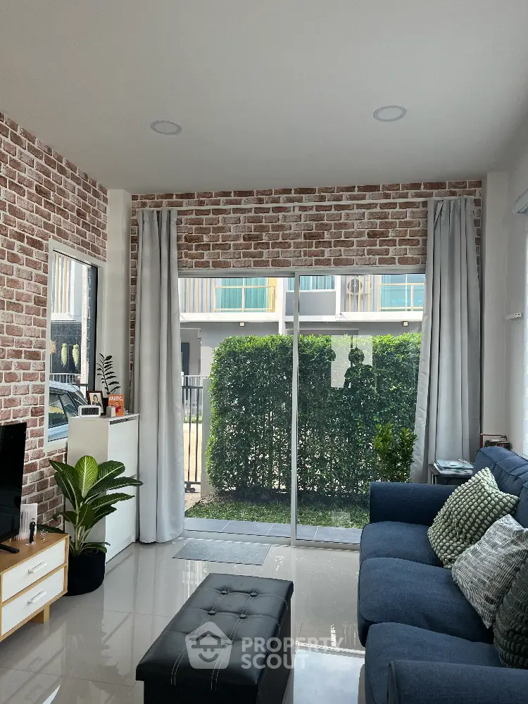 Modern living room with brick accent wall and large window overlooking garden