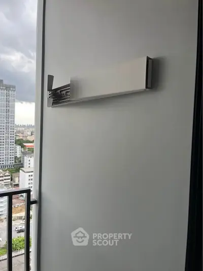 Modern balcony with sleek wall-mounted drying rack and city view.
