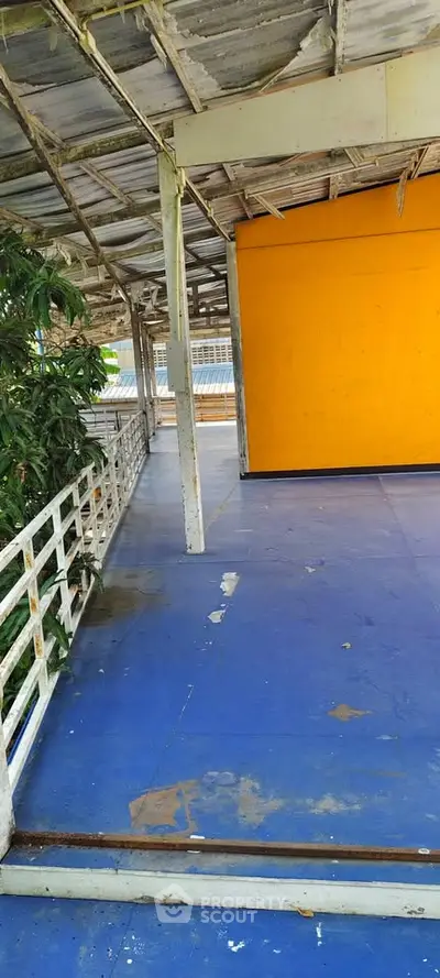 Spacious outdoor area with vibrant orange wall and blue flooring, perfect for creative renovations.