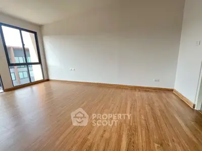 Spacious empty room with wooden flooring and large window