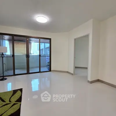 Spacious living room with large windows and balcony access, perfect for natural light lovers.
