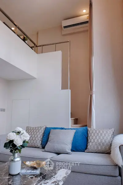 Modern living room with high ceiling and stylish decor, featuring a cozy sofa and elegant staircase.