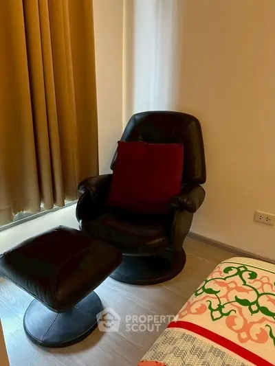 Cozy corner with leather armchair and footrest in modern bedroom setting.