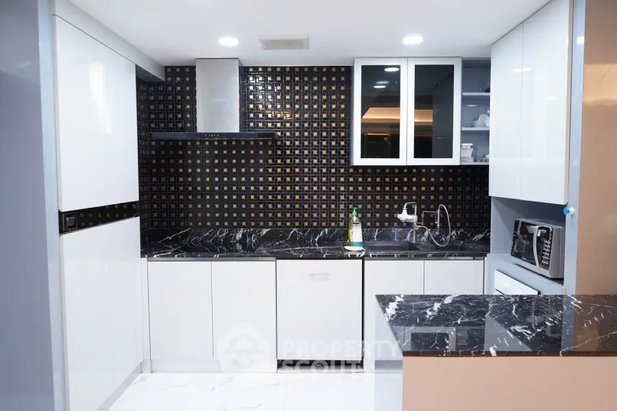 Modern kitchen with sleek black and white design, featuring marble countertops and stylish backsplash.