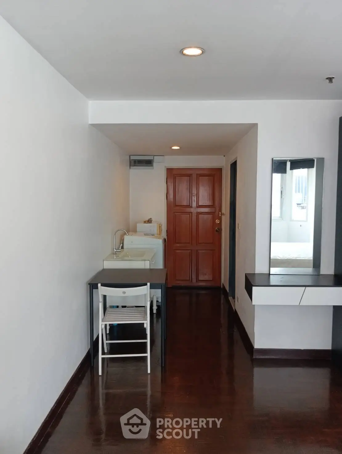 Cozy apartment interior with compact kitchen and wooden flooring, ideal for urban living.
