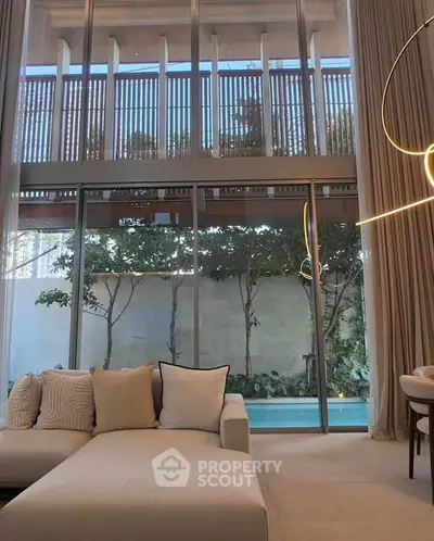 Luxurious living room with floor-to-ceiling windows and pool view, featuring elegant lighting and modern decor.