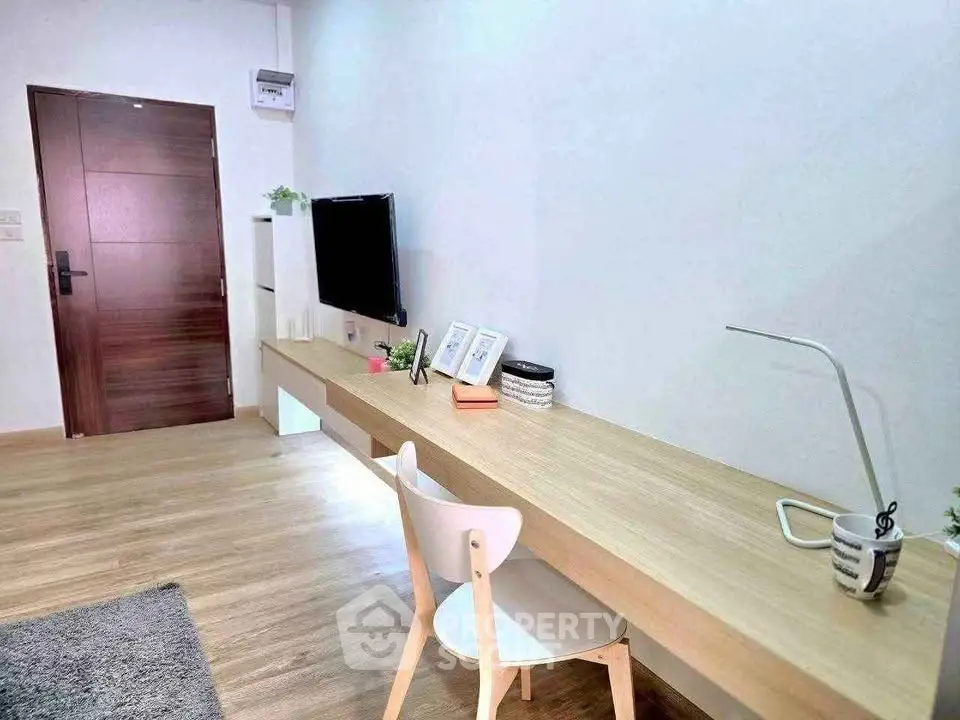 Modern study area with sleek wooden desk and wall-mounted TV in a stylish apartment.