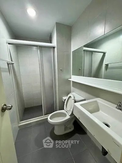 Modern bathroom with shower, toilet, and sink in sleek design.
