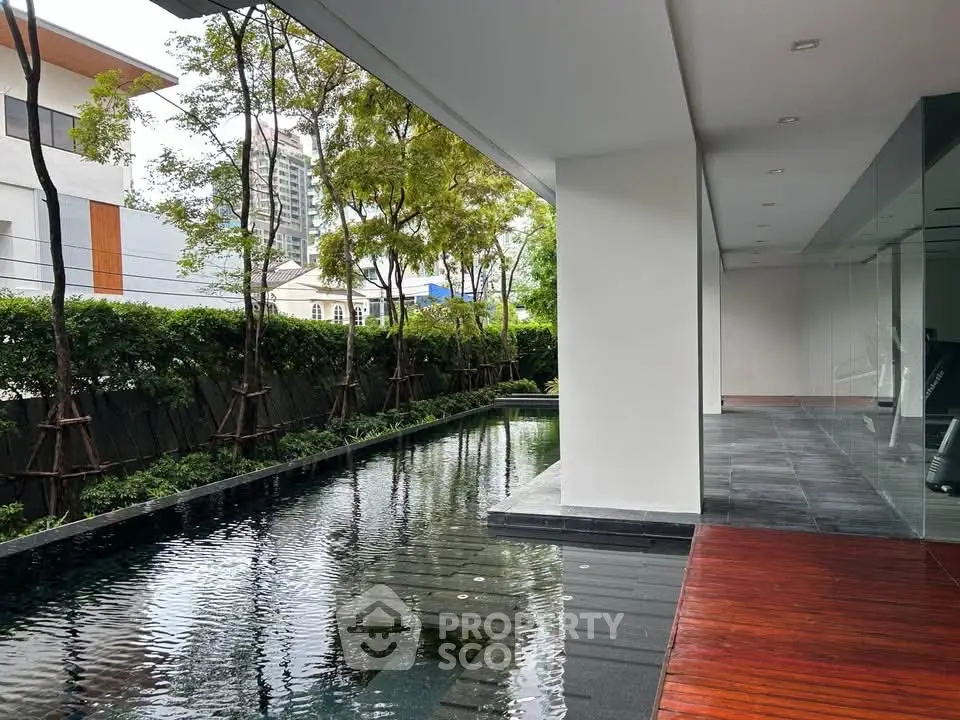 Luxurious modern building with sleek pool and lush greenery, perfect for relaxation and leisure.