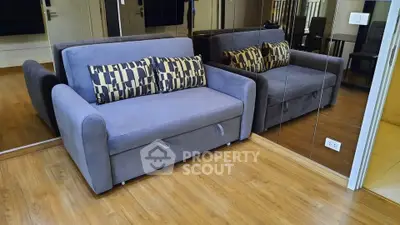 Modern living room with stylish gray sofa and mirrored wall