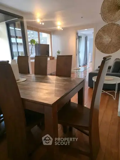 Spacious dining area with wooden table and chairs, open layout to living room, bright natural light.