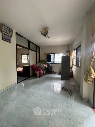 Spacious living area with tiled flooring and large windows for natural light.