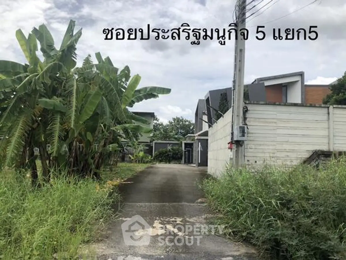 Modern residential property with lush greenery and private driveway in serene neighborhood.