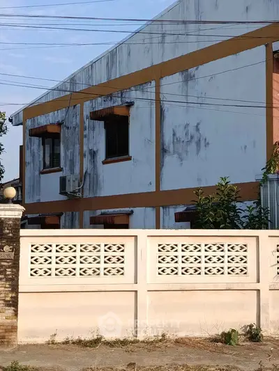Exterior view of a residential building with a white facade and decorative wall.