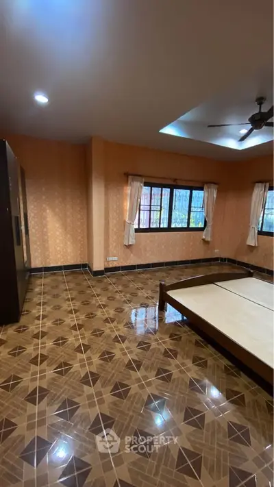 Spacious bedroom with patterned tile flooring and large windows for natural light.