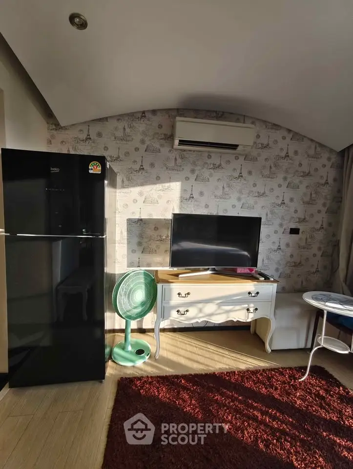Charming living room with modern decor, featuring a sleek black fridge, air conditioning, and stylish furniture.