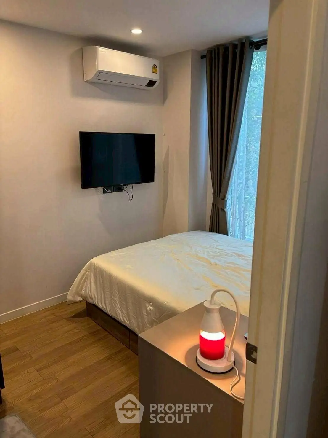 Cozy bedroom with modern decor, featuring a wall-mounted TV and air conditioning.