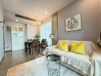 Modern living room with stylish decor and dining area, featuring cozy seating and elegant lighting.
