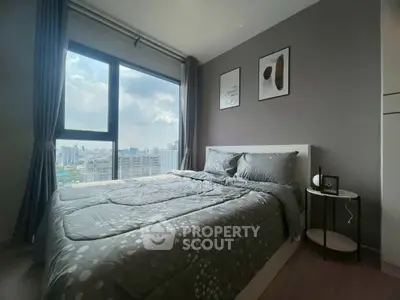 Modern bedroom with large window offering stunning city views, featuring stylish decor and cozy bedding.