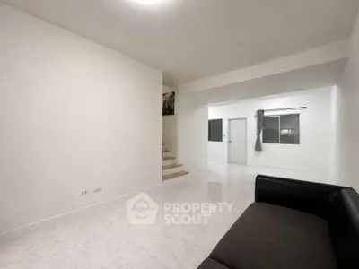 Spacious minimalist living room with sleek white walls and modern staircase