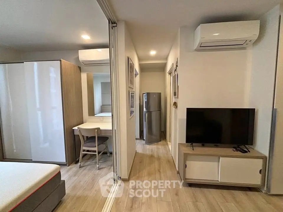 Modern studio apartment with sleek design, featuring air conditioning, flat-screen TV, and compact kitchen area.