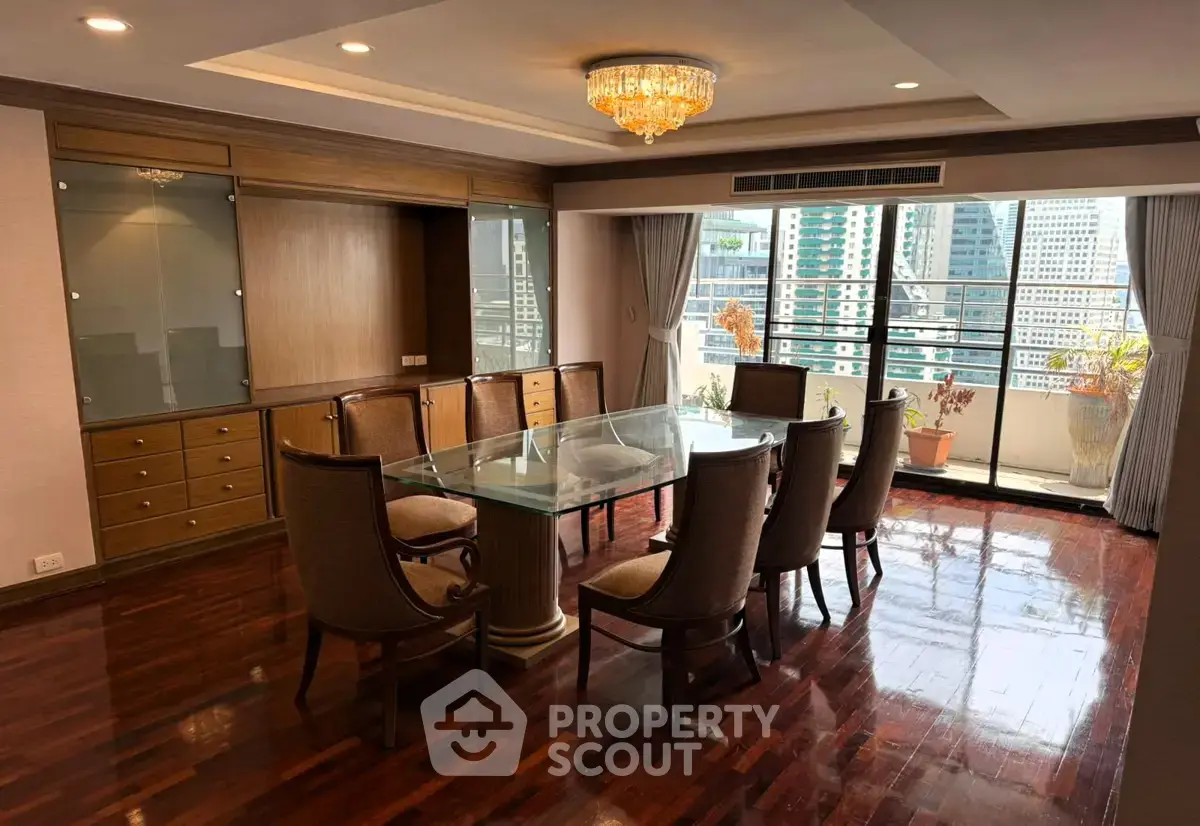 Elegant dining room with glass table and city view, featuring hardwood floors and chandelier lighting.
