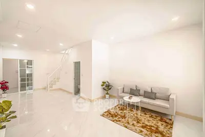 Spacious modern living room with elegant white decor and cozy seating area.