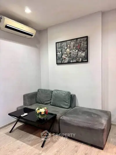 Modern living room with stylish gray sofa, chic black coffee table, and urban wall art, perfect for cozy relaxation.