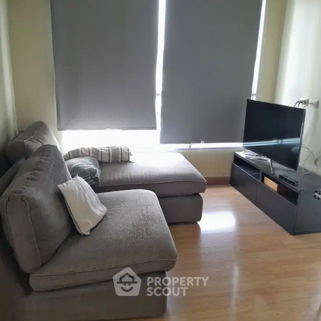Cozy living room with modern gray sofa and flat-screen TV, perfect for relaxation.