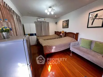Cozy bedroom with twin beds, modern decor, and wooden flooring in a stylish apartment.