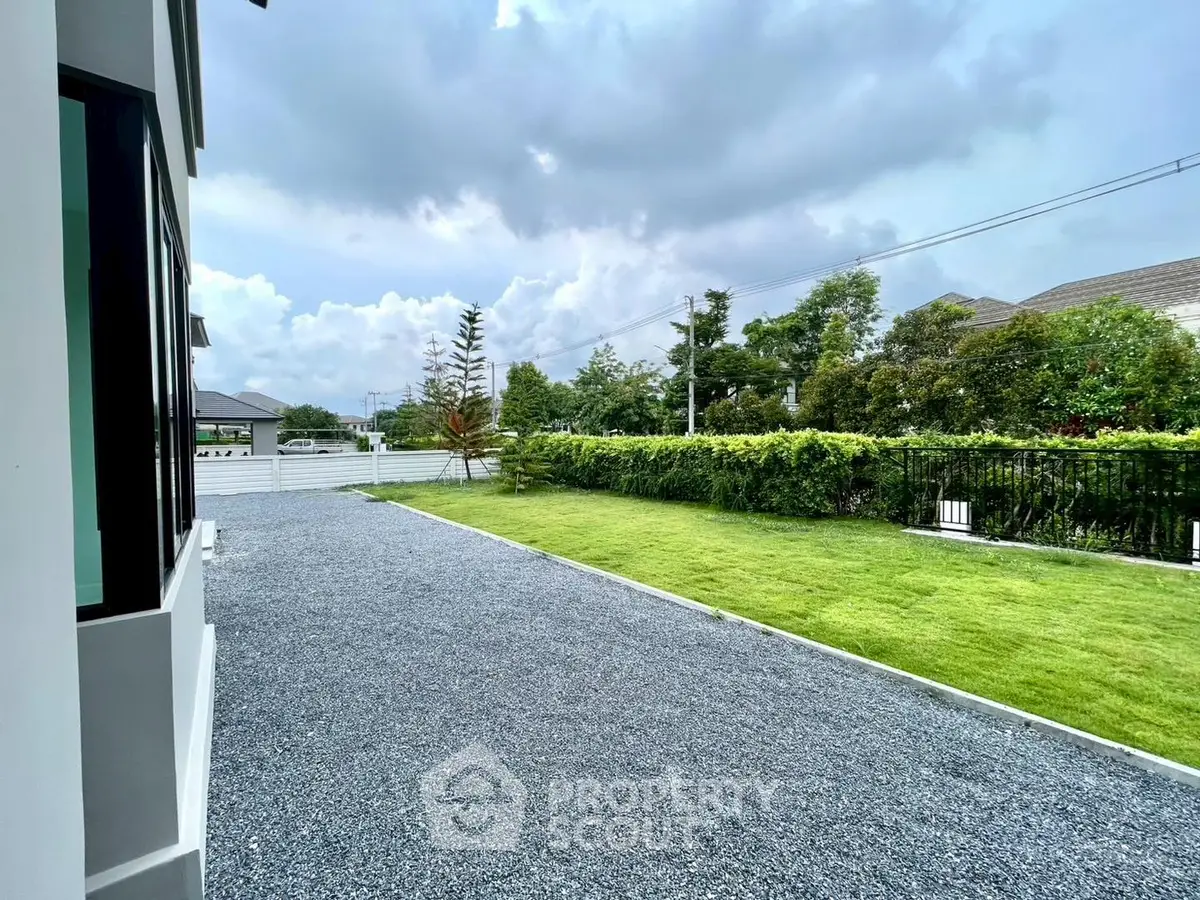 Spacious garden with lush greenery and gravel pathway in modern residential property