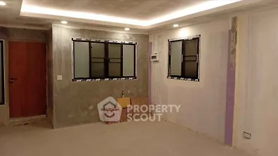 Unfinished room with modern lighting and windows, ready for customization.