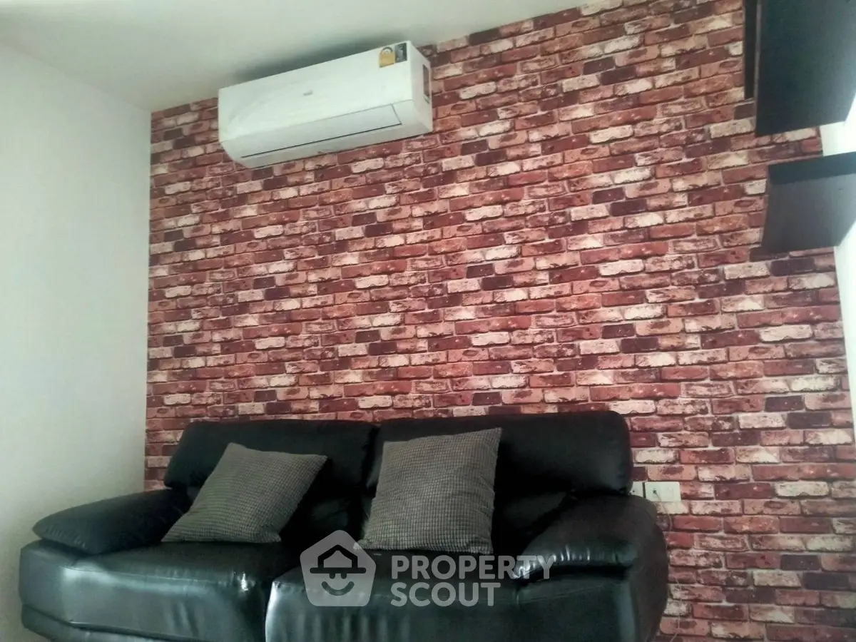 Stylish living room with brick accent wall and modern black leather sofa.