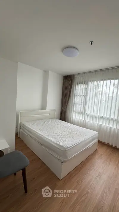 Bright and cozy bedroom with large window and modern furnishings.