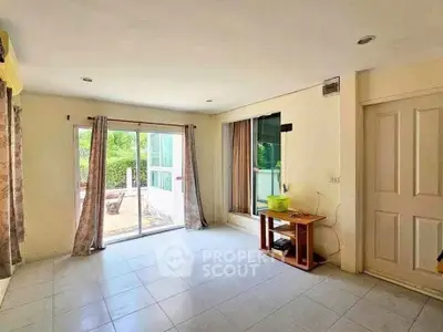 Spacious living room with large windows and garden view, perfect for natural light lovers.