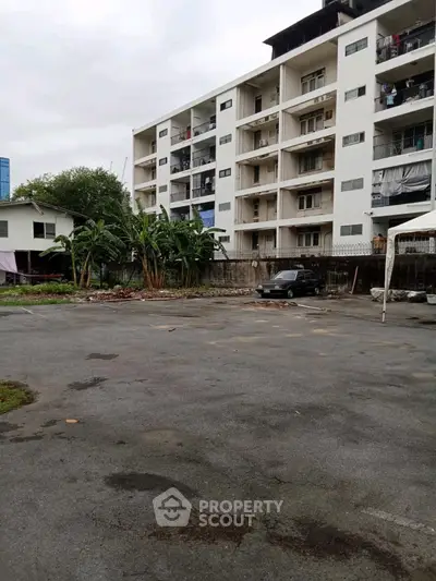 Spacious apartment building with ample parking space and lush greenery.