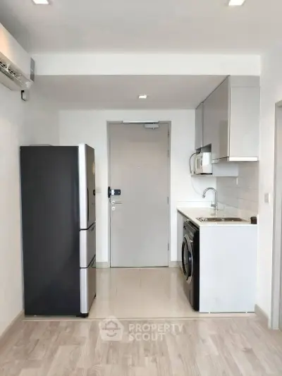 Modern compact kitchen with fridge and washing machine in sleek apartment.