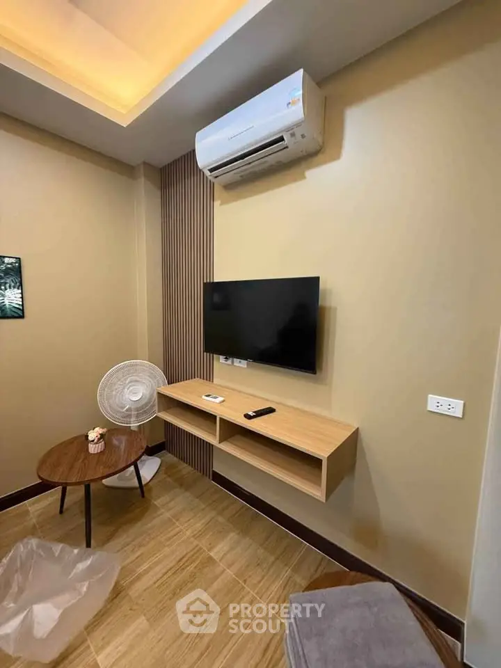 Modern living room with wall-mounted TV and air conditioning unit, featuring stylish wooden flooring.