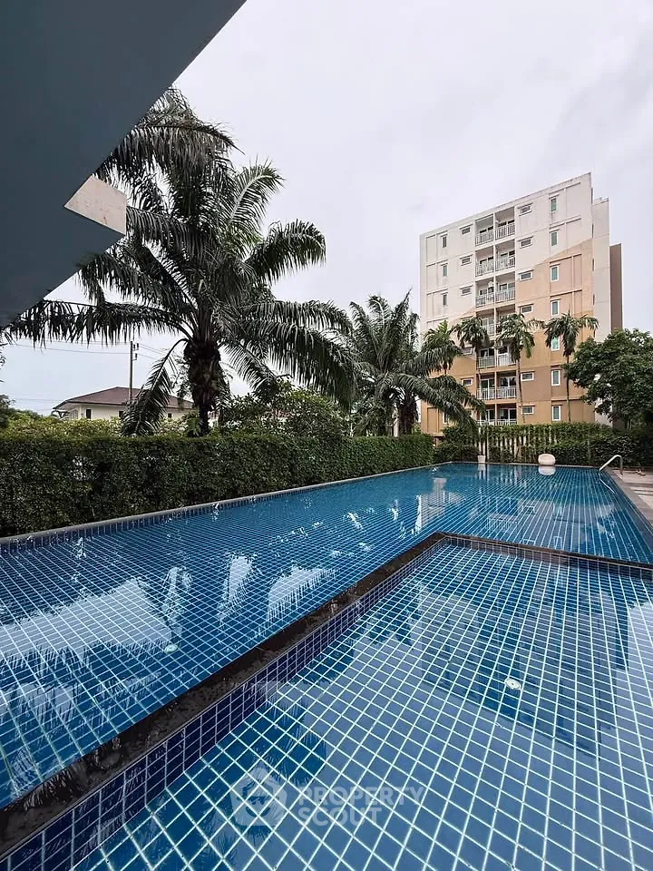 Luxurious outdoor pool with palm trees and modern building backdrop, perfect for relaxation and leisure.