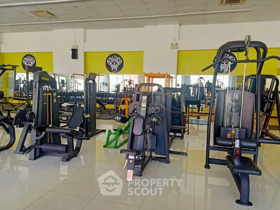 Spacious gym with modern fitness equipment and bright interior design.