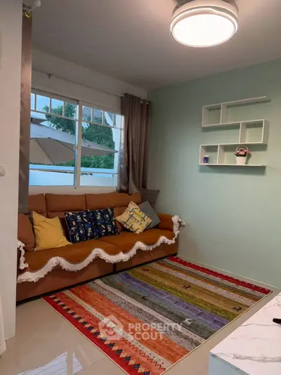 Cozy living room with colorful rug and stylish shelving, perfect for relaxation and entertaining.