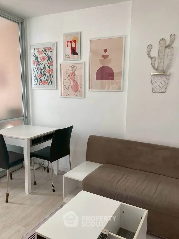 Modern living room with stylish decor, featuring a cozy sofa, dining table, and artistic wall frames.
