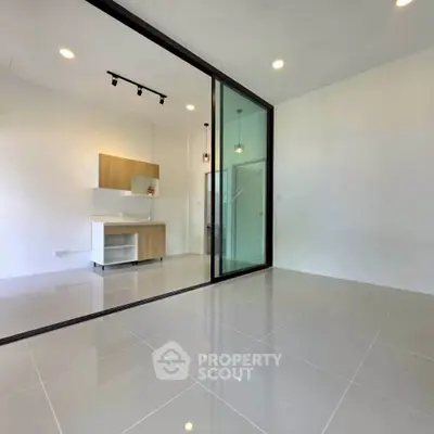 Modern open-plan living space with sleek kitchen and glass partition